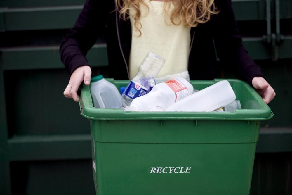 Teenager holding green recycling bin